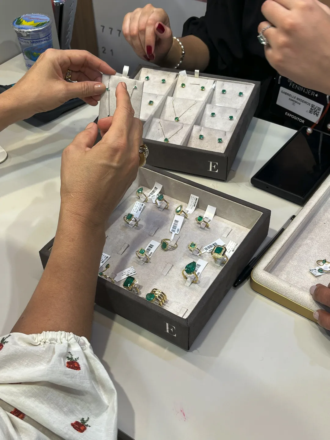 MYNE Joalheria — vitrine de anéis e colares com esmeraldas